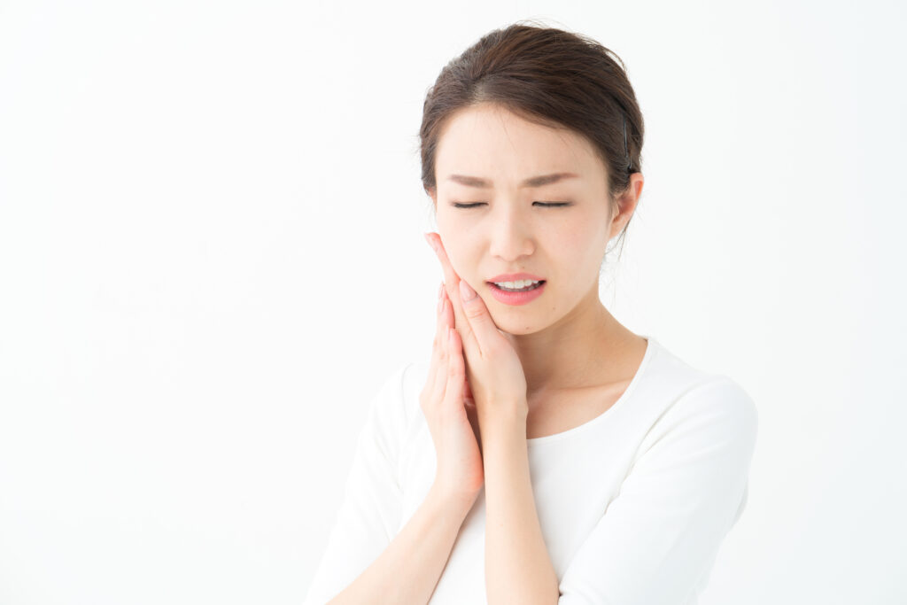 歯の痛みに耐えて顎を抑える女性