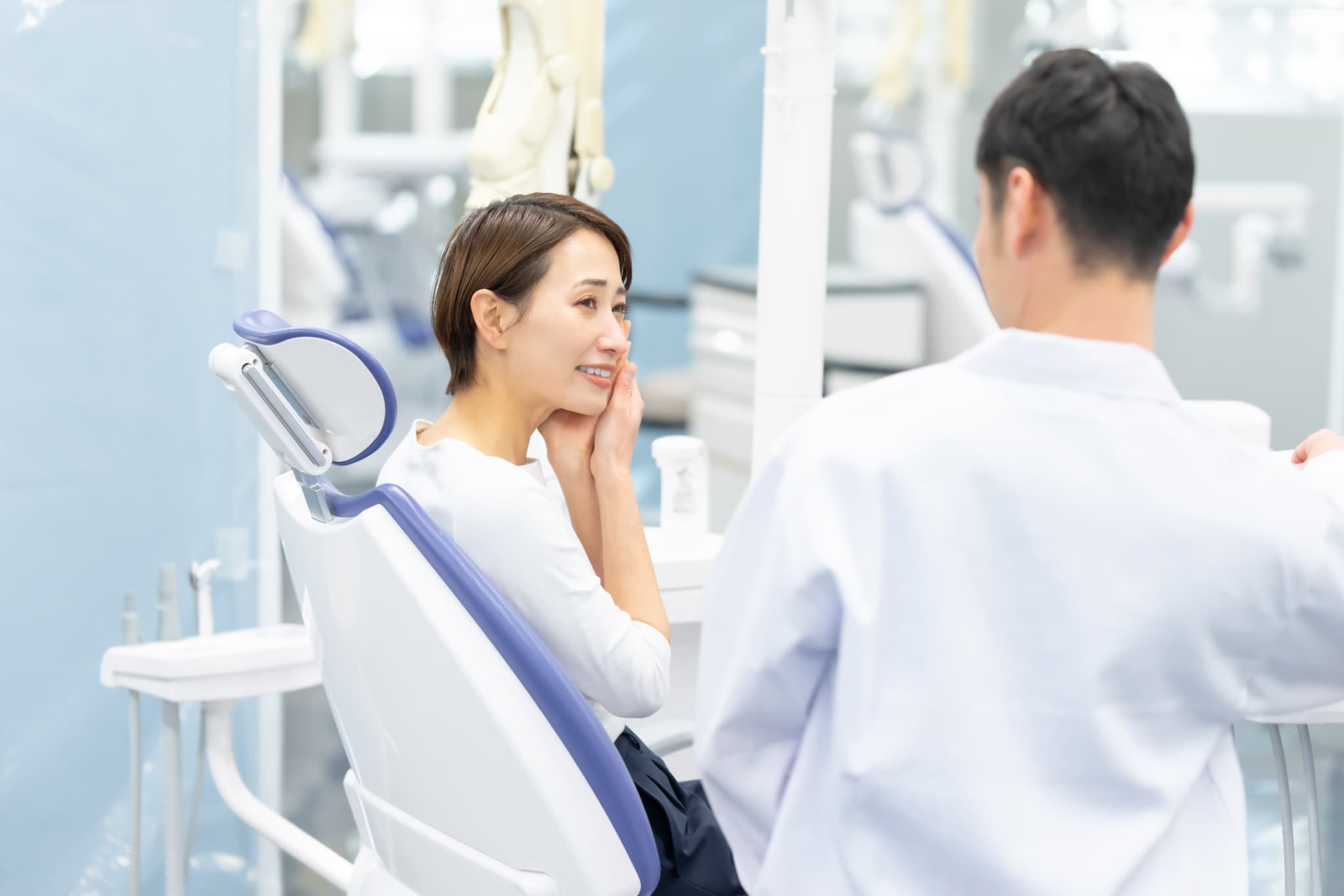 歯科医師に親知らずが虫歯になった場合の治療法を尋ねる女性