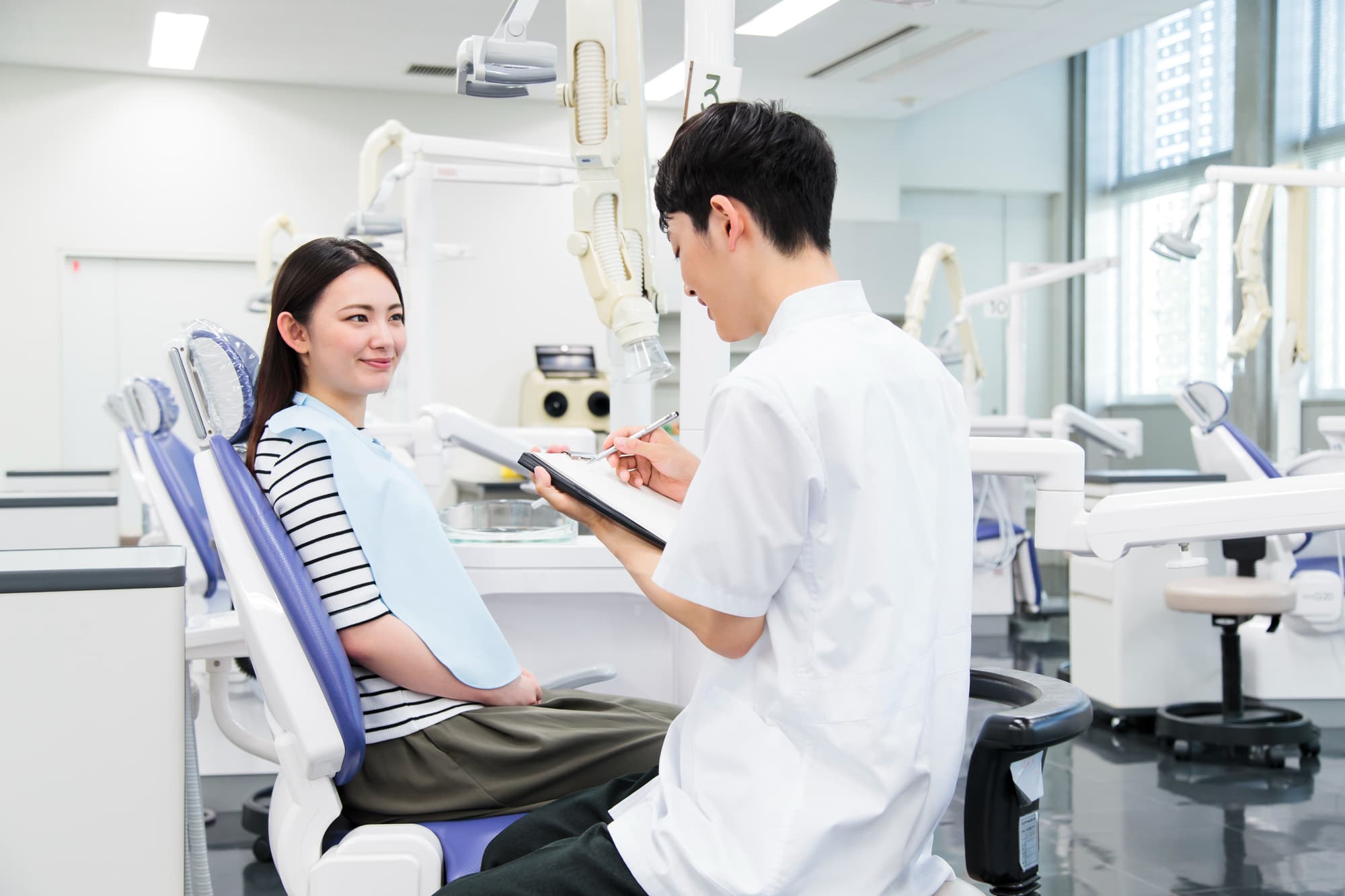 矯正治療中に虫歯ができて歯科医院を受診する女性と歯科医師
