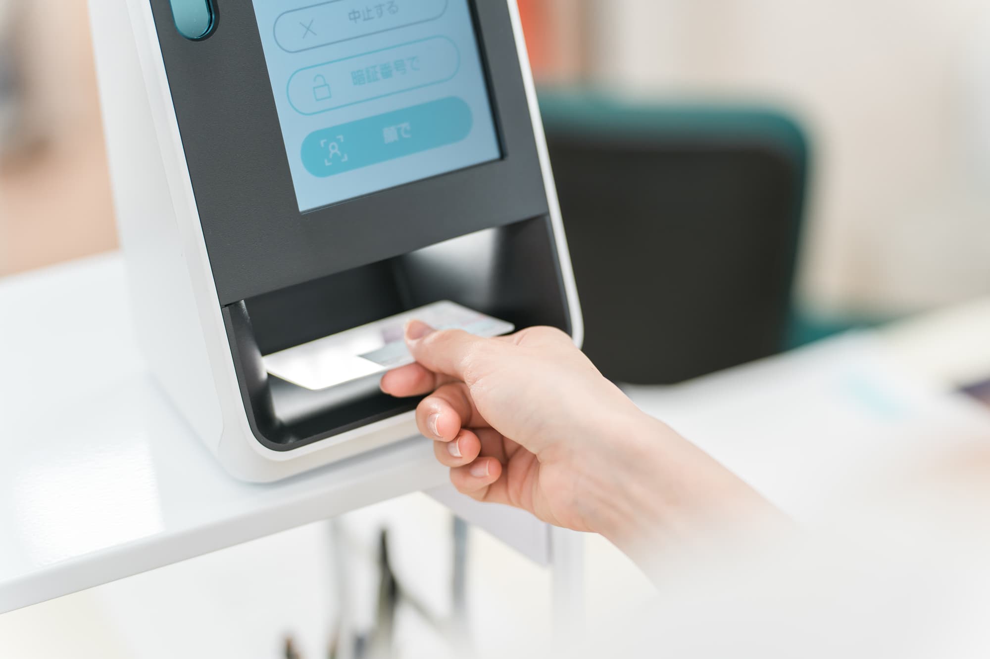 歯科医院の受付でマイナンバーカードをカードリーダーで読み込む女性の手元