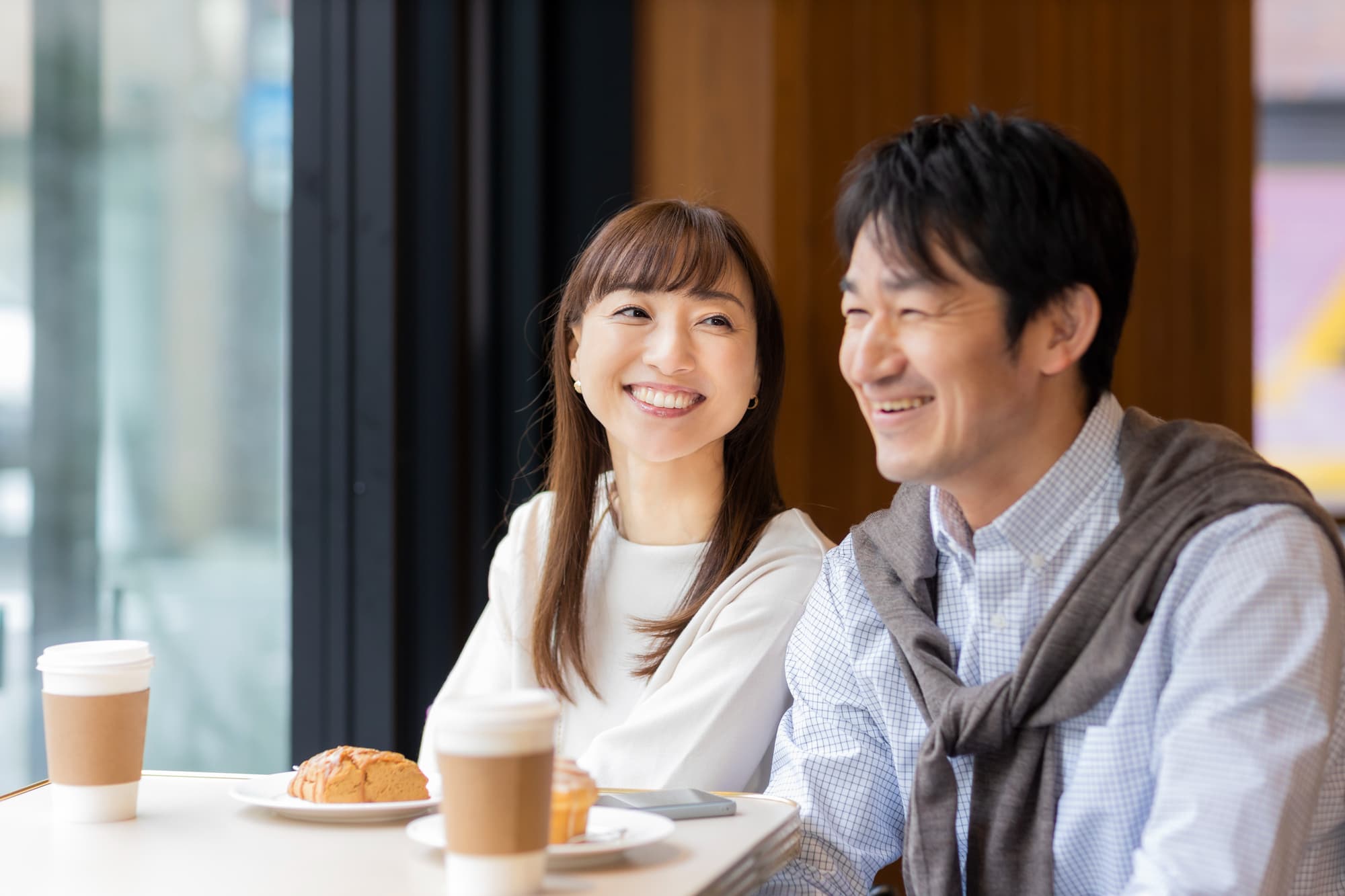 適切なケアをしたセラミックの綺麗な歯でカフェタイムを楽しむ男女