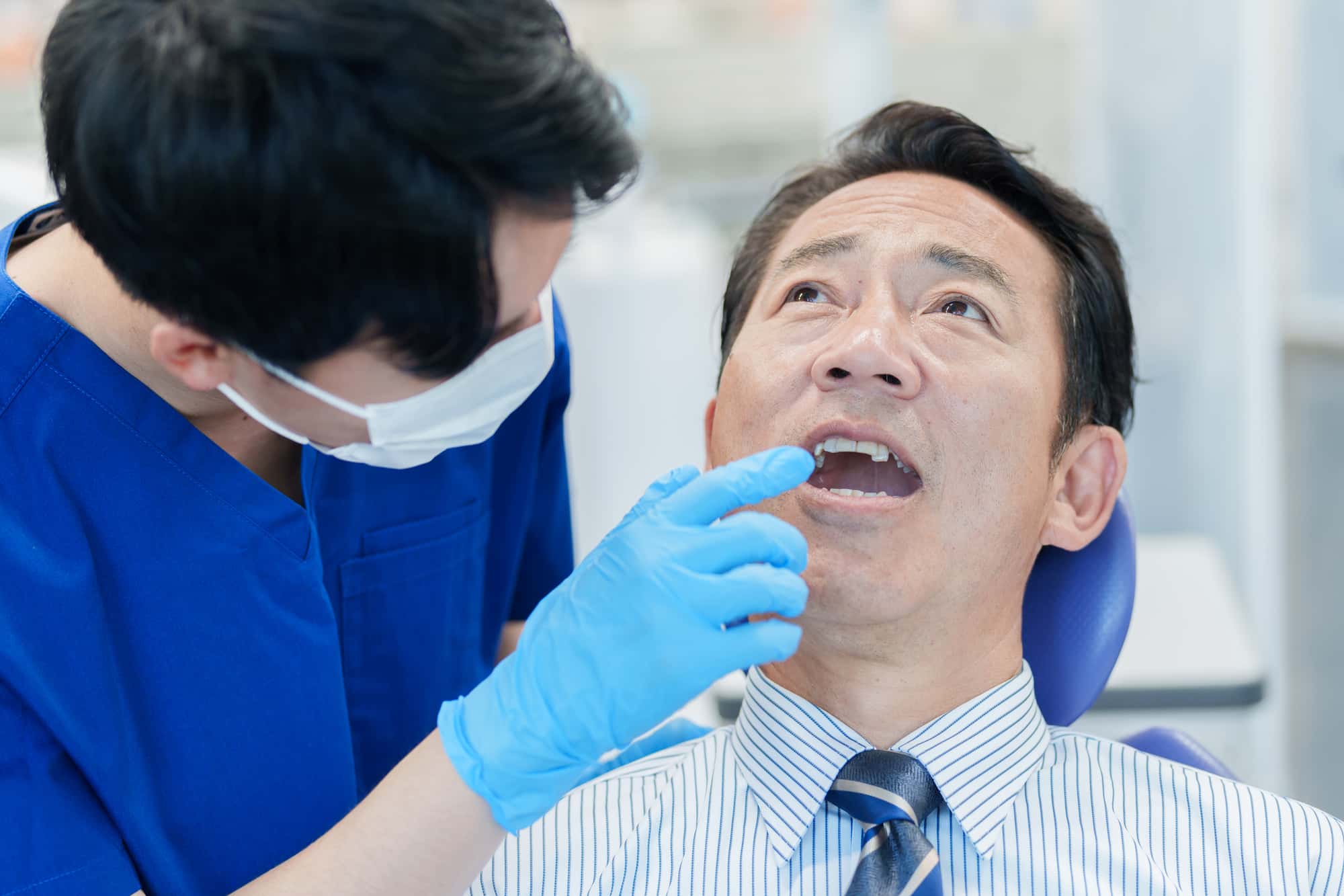 セラミックの歯が割れて歯科医に確認してもらう男性