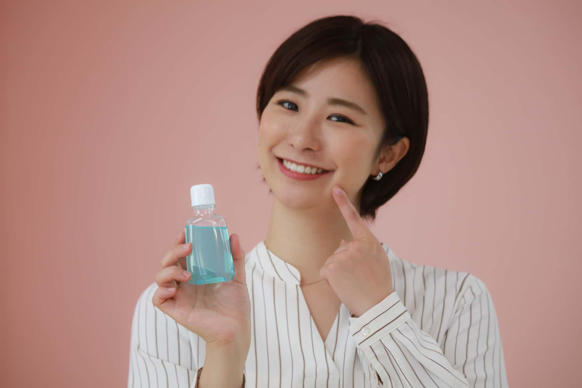 マウスピースを手に持ち口を指さしている女性